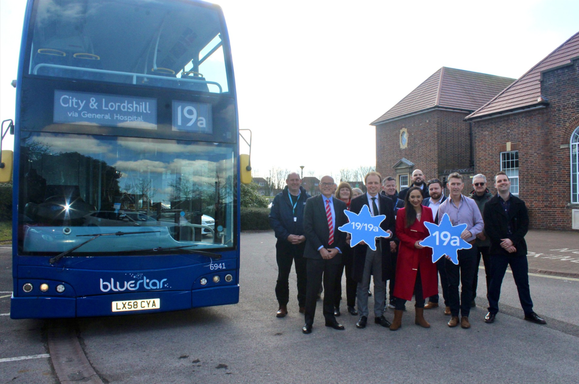 Stakeholders in a group next to a Bluestar 19a bus