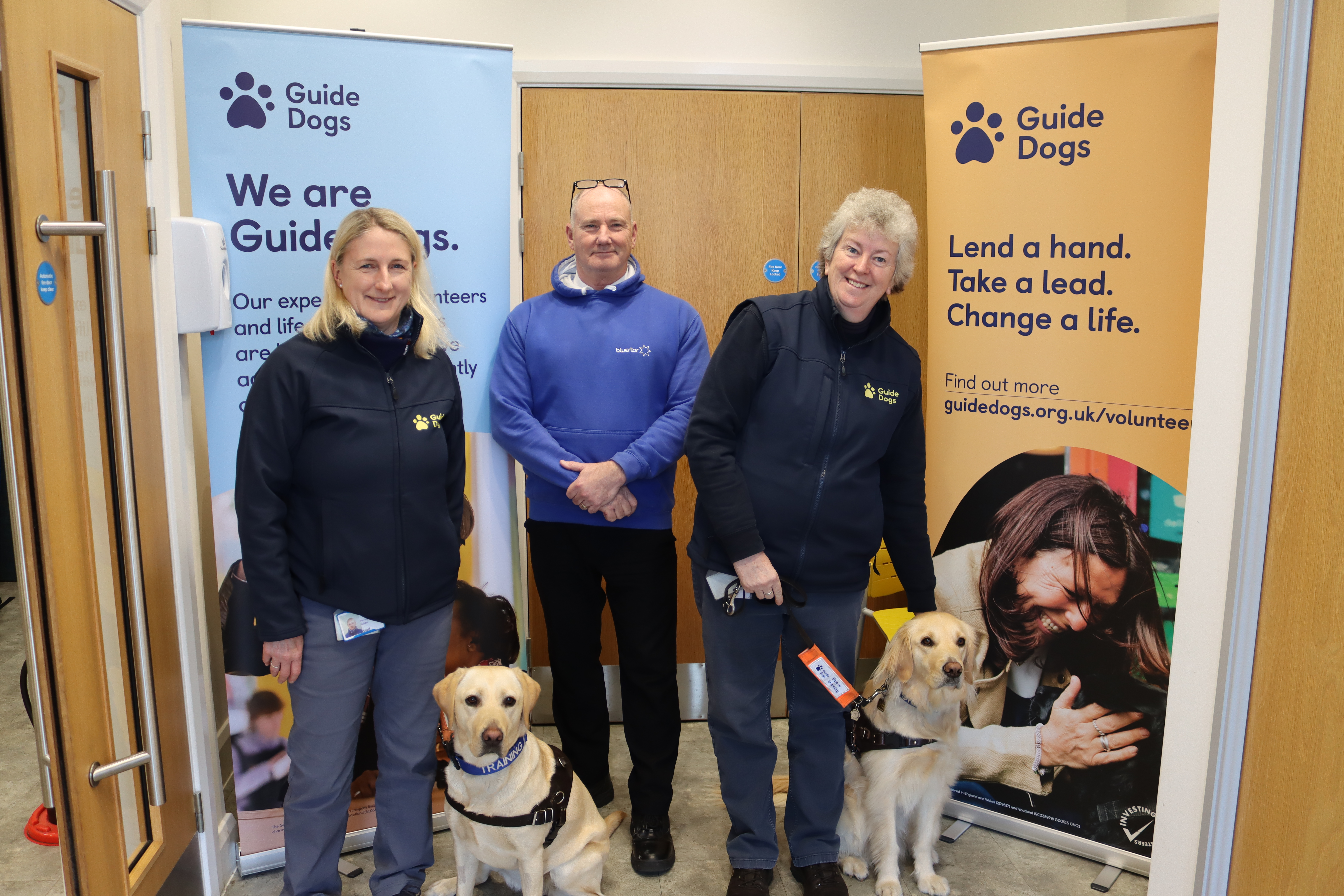 Bluestar representative with two guide dogs and their trainers