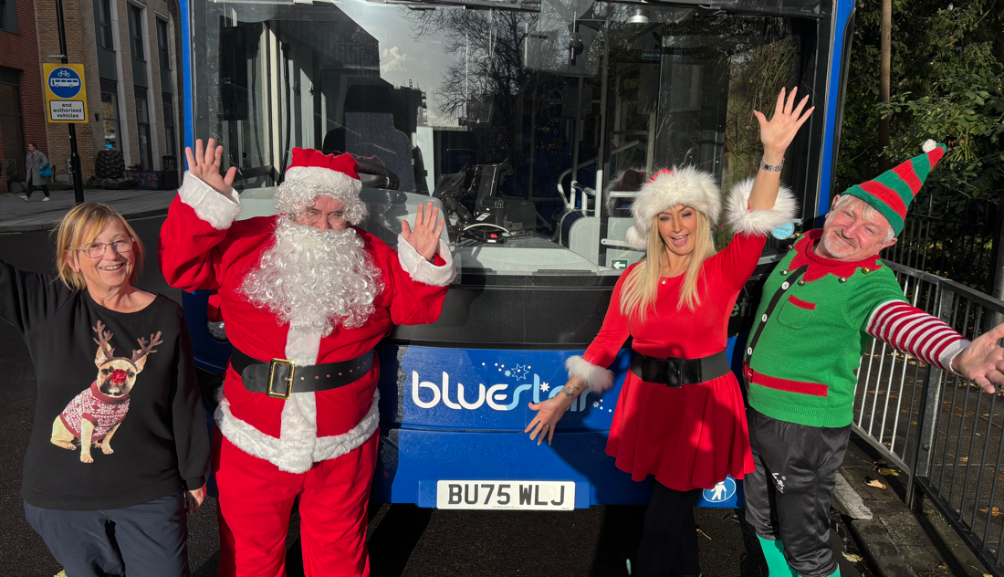 Bus drivers dressed in Christmas outfits in front of a bus