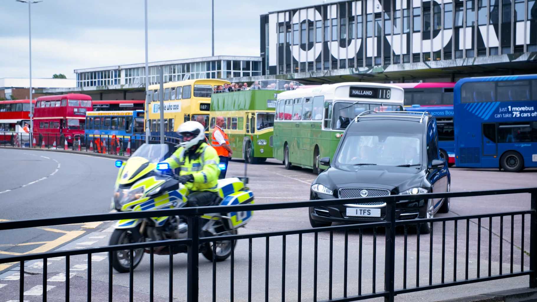 police bike leading funeral cortege of buses