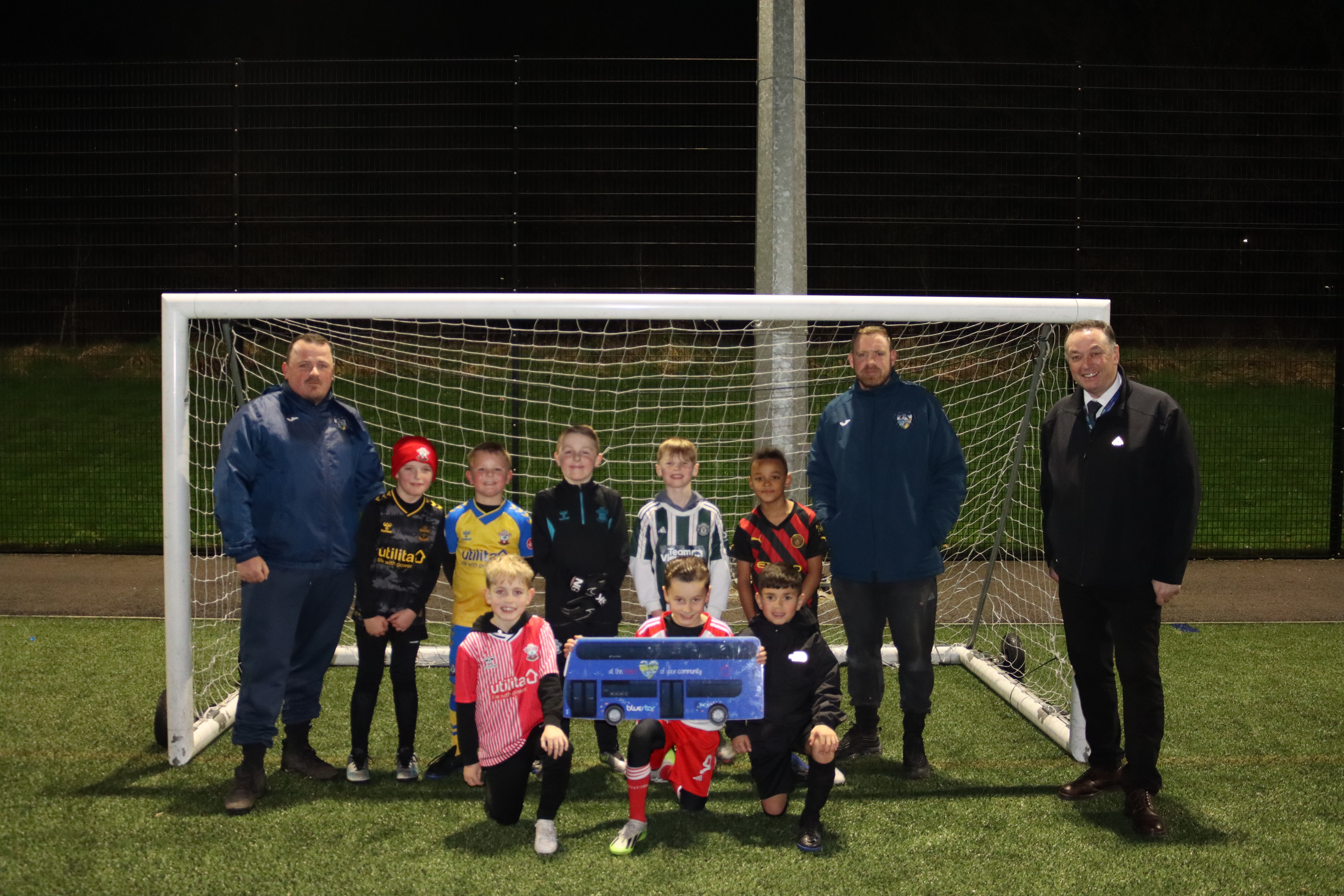 Hamble under 9s football team in a goal with their managers and Bluestar operations manager