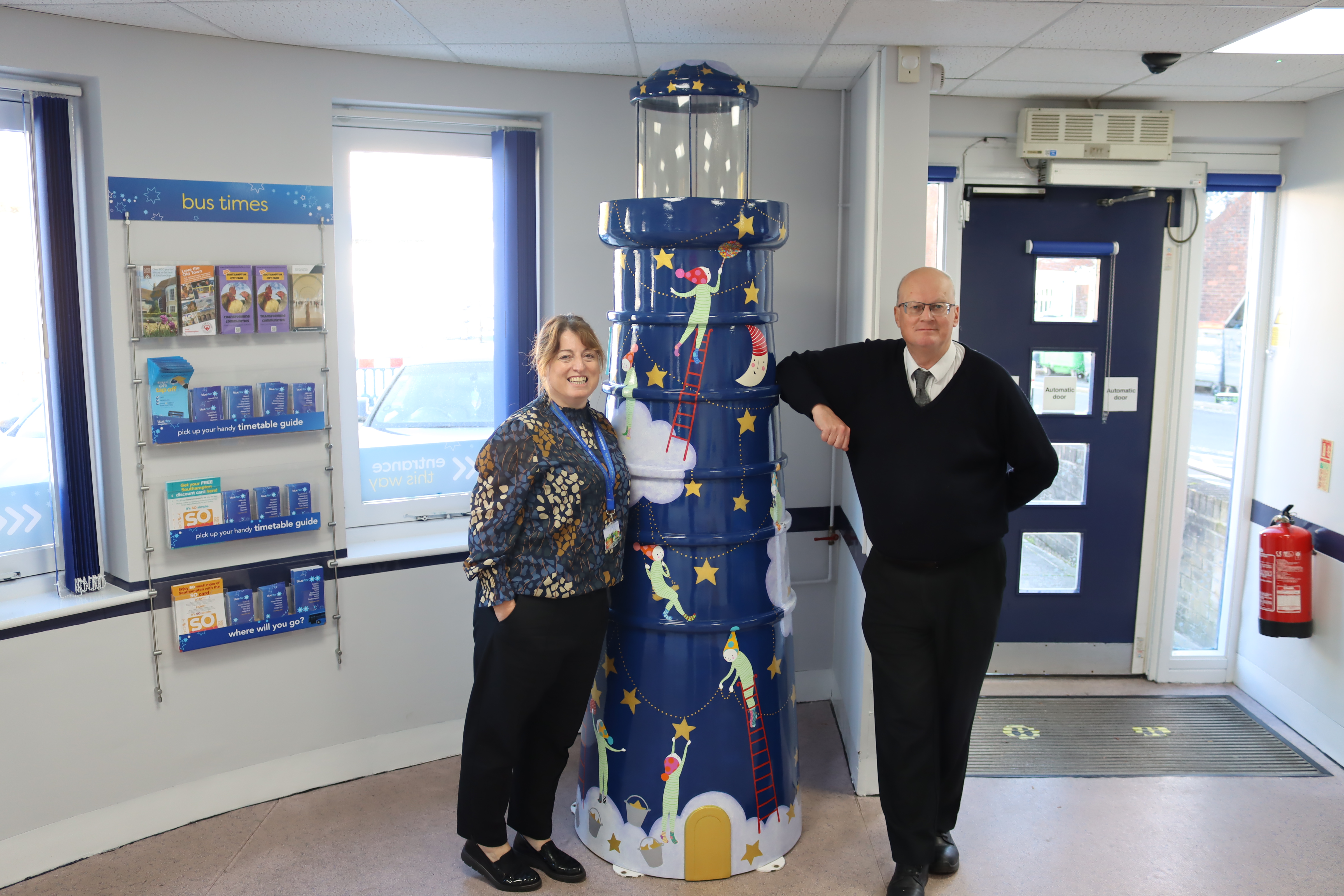 Bluestar operations manager and travel shop adviser with lighthouse sculpture 
