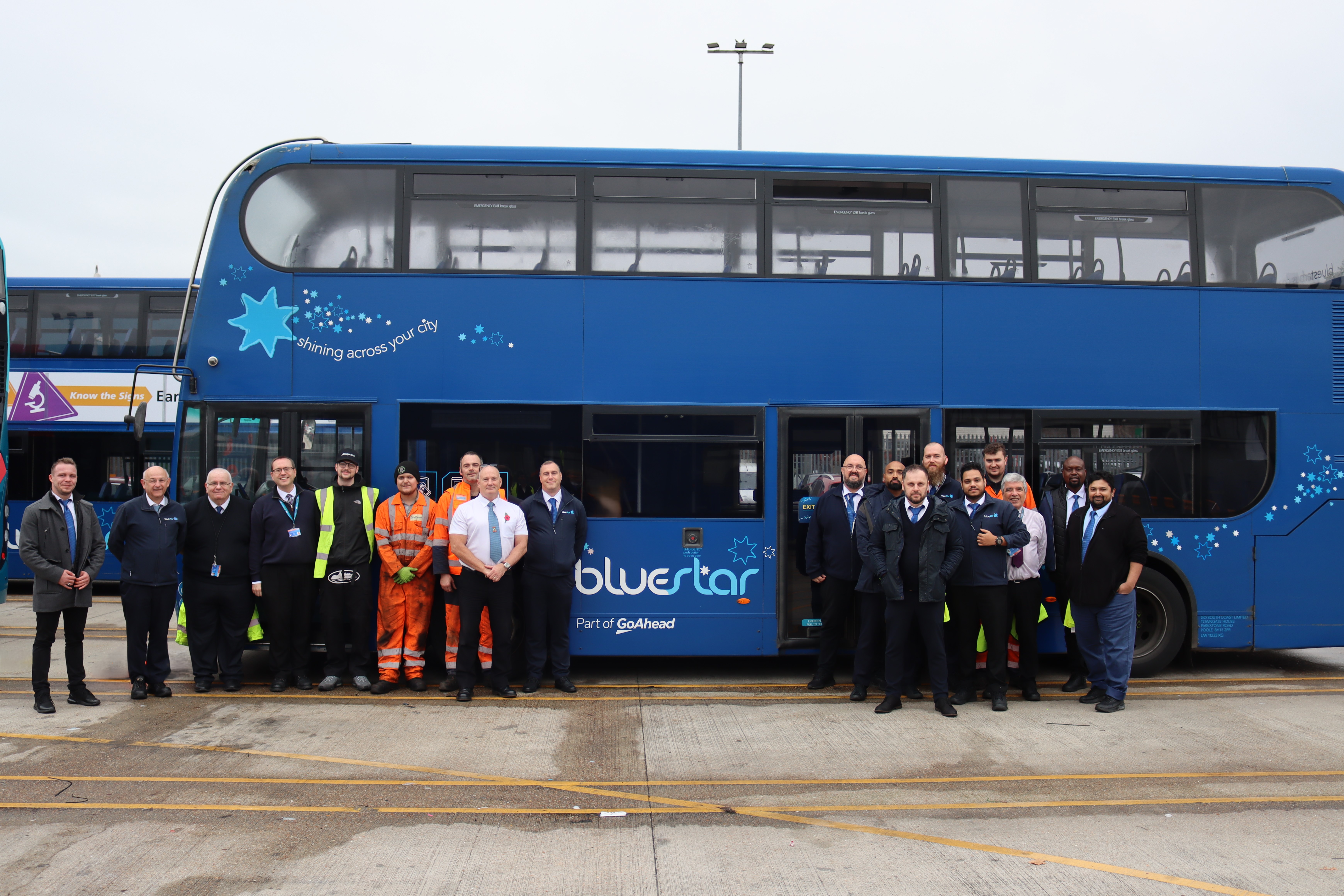 Group of men from Bluestar stood around a bus