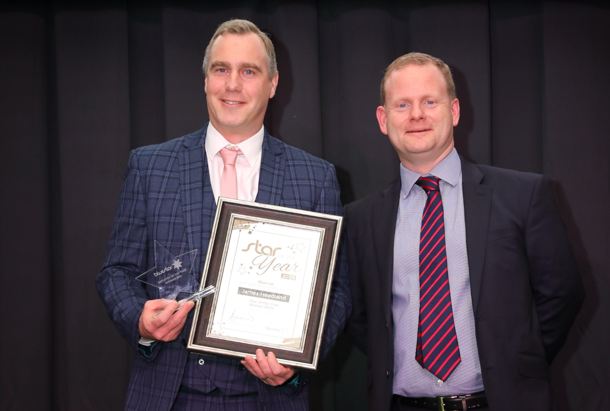 James Headland stood next to MD Ed Wills with his certificate and trophy