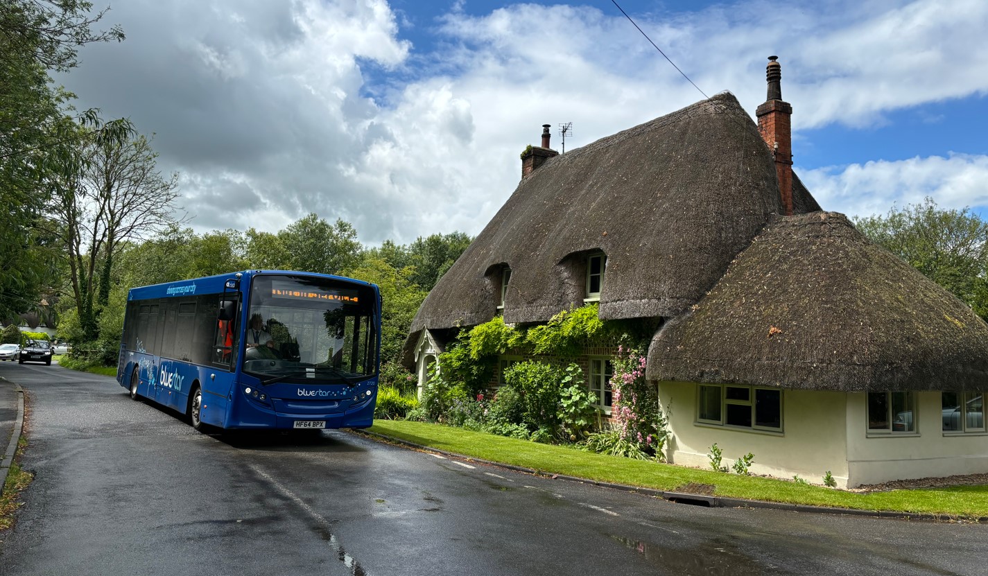 Bluestar single decker bus outside a thatched cottage