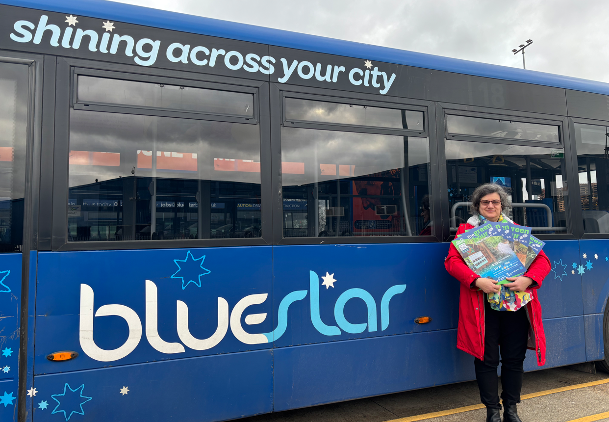 Lady stood next to a Bluestar bus holding posters