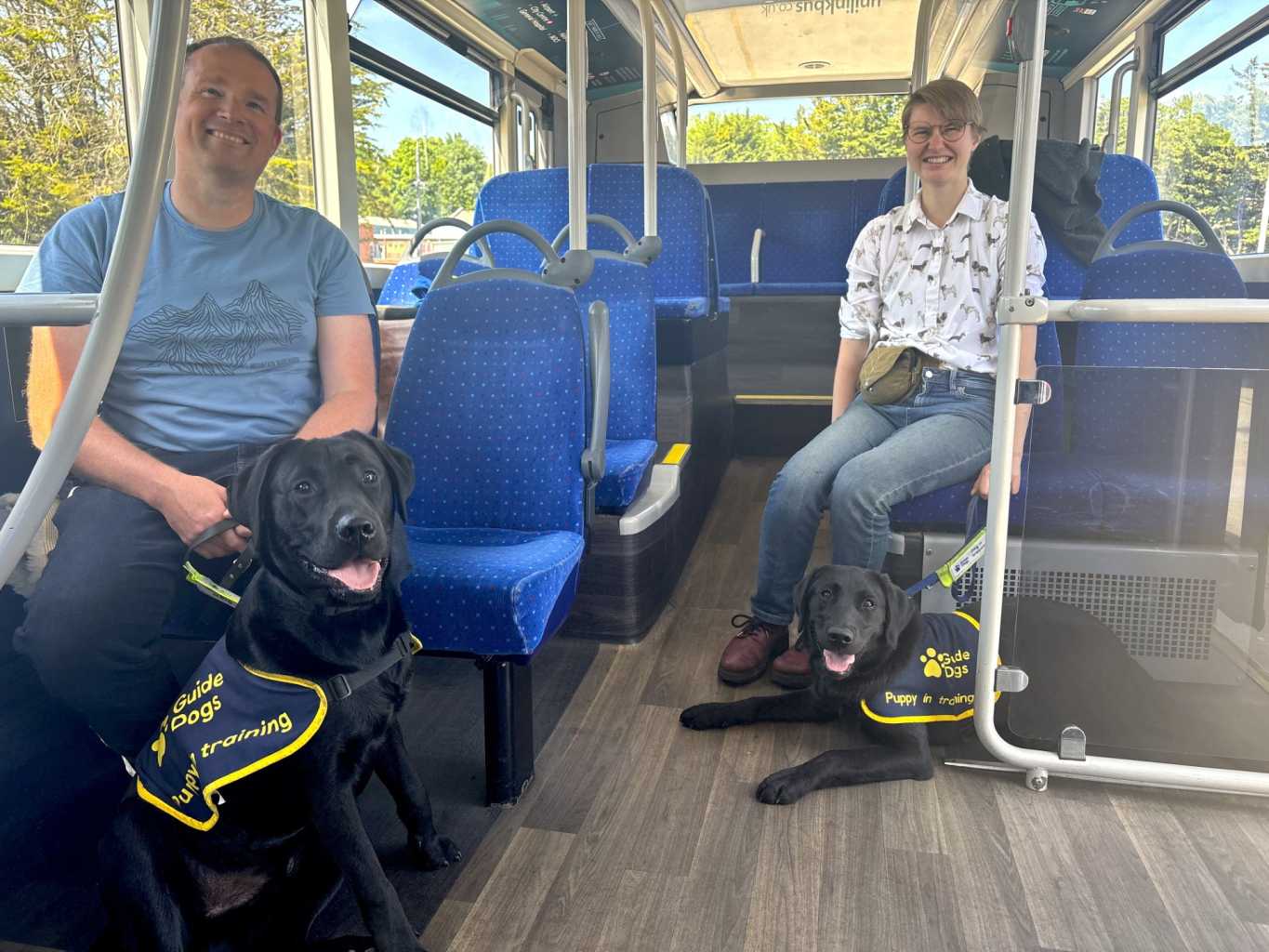 picture of two guide dogs and their trainers sat on a bus